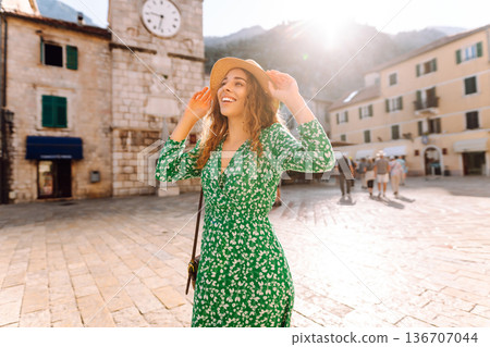 Young woman in a green dress smiles while using her yellow smartphone. Travel, tourism, technology Young woman in a green dress smiles while using her yellow smartphone. Travel, tourism, technology 136707044