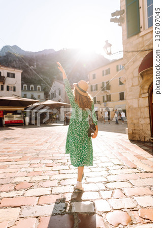 Young woman in a green dress smiles while using her yellow smartphone. Travel, tourism, technology 136707045