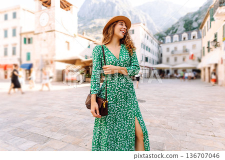 Young woman in a green dress smiles while using her yellow smartphone. Travel, tourism, technology 136707046