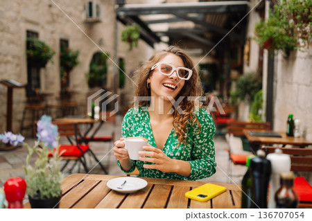 Happy young woman drinking tea, coffee while sitting in a Cafe. People, fashion, lifestyle Happy young woman drinking tea, coffee while sitting in a Cafe. People, fashion, lifestyle 136707054