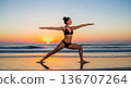 Woman practicing yoga warrior pose at beach sunset 136707264