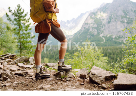 Close-up of female legs in hiking boots on a hiking trail. Travel, vacation. The concept of nature. Close-up of female legs in hiking boots on a hiking trail. Travel, vacation. The concept of nature. 136707428