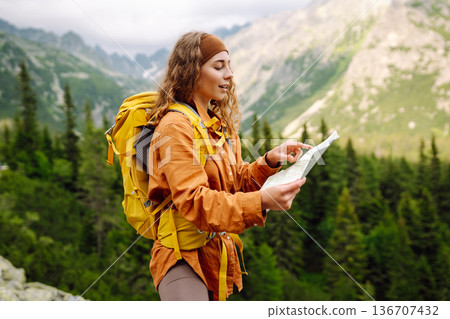 The adventure begins! Beautiful woman traveler with a yellow backpack, holds a map. Vacation concept The adventure begins! Beautiful woman traveler with a yellow backpack, holds a map. Vacation concept 136707432