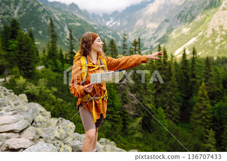 The adventure begins! Beautiful woman traveler with a yellow backpack, holds a map. Vacation concept The adventure begins! Beautiful woman traveler with a yellow backpack, holds a map. Vacation concept 136707433