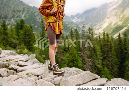 Close-up of female legs in hiking boots on a hiking trail. Travel, vacation. The concept of nature. Close-up of female legs in hiking boots on a hiking trail. Travel, vacation. The concept of nature. 136707434