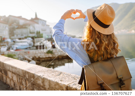 Woman tourist holding hands in shape of heart looking at panoramic landscape of city. Lifestyle. 136707627