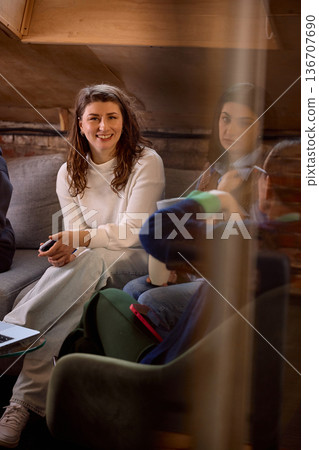 Young professional woman smiling during informal team meeting on sofa. Young professional woman smiling during informal team meeting on sofa. 136707690