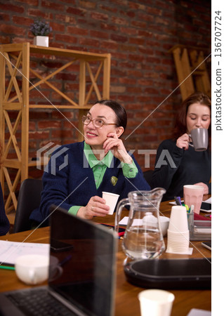 Senior businesswoman listening during team meeting in office. Senior businesswoman listening during team meeting in office. 136707724
