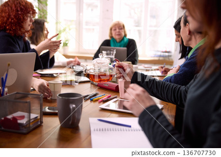 Women team discussing ideas around table during office meeting. 136707730