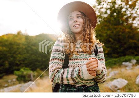 Young woman enjoys sunny afternoon in mountains while sitting on rocks. Tourism. Active lifestyle. Young woman enjoys sunny afternoon in mountains while sitting on rocks. Tourism. Active lifestyle. 136707796