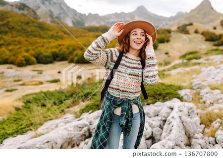 Young woman enjoys sunny afternoon in mountains while sitting on rocks. Tourism. Active lifestyle. Young woman enjoys sunny afternoon in mountains while sitting on rocks. Tourism. Active lifestyle. 136707800