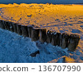 Wooden breakwaters frozen in ice and snow in the Baltic Sea 136707990