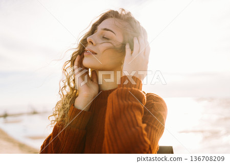 Woman enjoying breezy day near vibrant red lighthouse at sunset. Travel, weekend, lifestyle concept. Woman enjoying breezy day near vibrant red lighthouse at sunset. Travel, weekend, lifestyle concept. 136708209