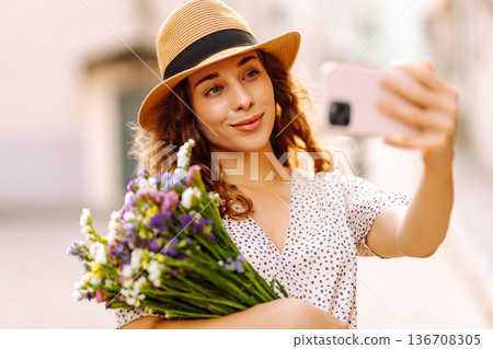 Selfie time. Young woman with a bouquet of wild flowers posing on the street. Fashion style. Selfie time. Young woman with a bouquet of wild flowers posing on the street. Fashion style. 136708305