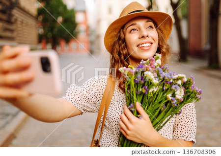 Selfie time. Young woman with a bouquet of wild flowers posing on the street. Fashion style. Selfie time. Young woman with a bouquet of wild flowers posing on the street. Fashion style. 136708306