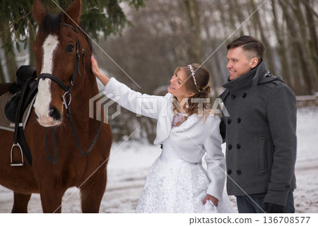 Newlyweds Standing Beside Horse In Snowy Landscape Newlyweds Standing Beside Horse In Snowy Landscape 136708577