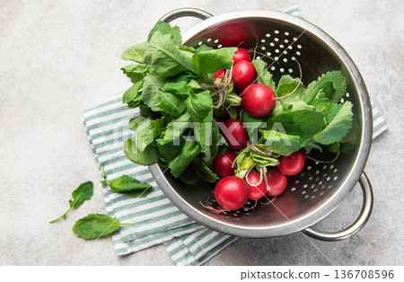 Fresh radishes with green tops in colander 136708596