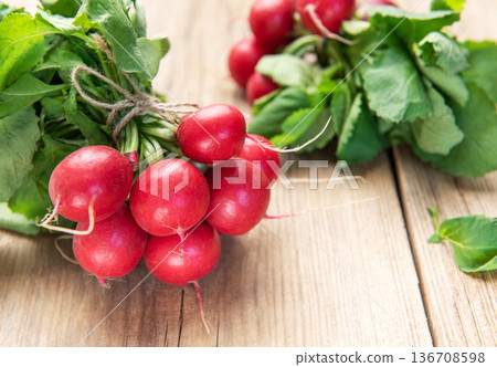 Fresh organic radishes with green leaves on rustic wood 136708598