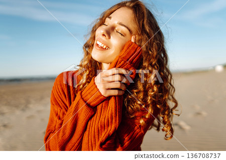 Portrait of a beautiful woman on beach in cold weather. Autumn mood. Travel, nature, weekend, relax. 136708737
