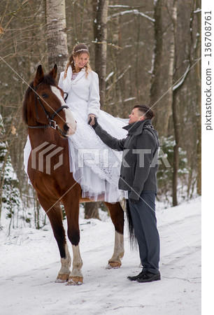 Groom Assisting Bride Dismounting Horse In Winter Groom Assisting Bride Dismounting Horse In Winter 136708761