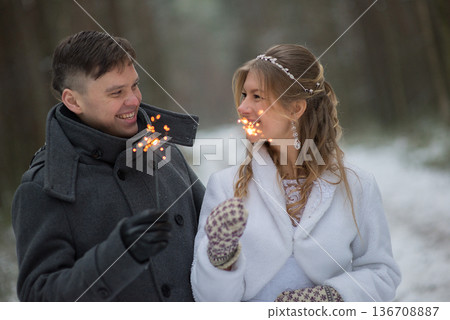 Bride and Groom Laughing with Sparklers in Winter Forest 136708887