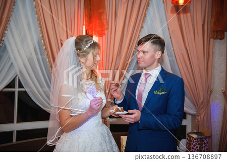 Newlyweds Sharing Wedding Cake In Cozy Evening Atmosphere Newlyweds Sharing Wedding Cake In Cozy Evening Atmosphere 136708897