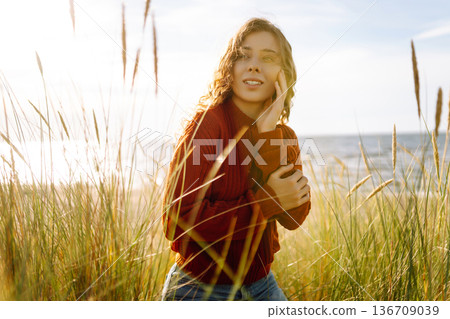 Happy woman enjoying nature outdoors in tall grass. Flying hairs. Outdoor. Fashion style. 136709039