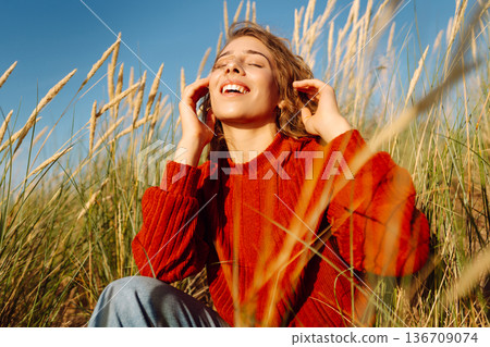Happy woman enjoying nature outdoors in tall grass. Flying hairs. Outdoor. Fashion style. 136709074