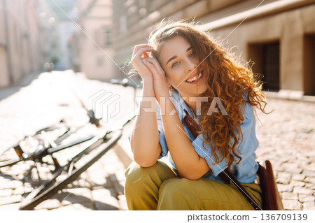 Beautiful smiling woman sitting next to bike on the street city. Adventure Concept 136709139