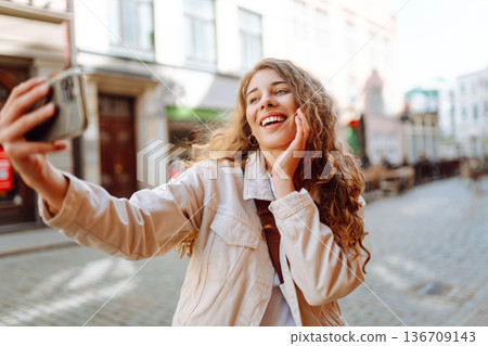 Lifestyle selfie portrait of young positive woman having fun and taking selfie in city. Active life. Lifestyle selfie portrait of young positive woman having fun and taking selfie in city. Active life. 136709143