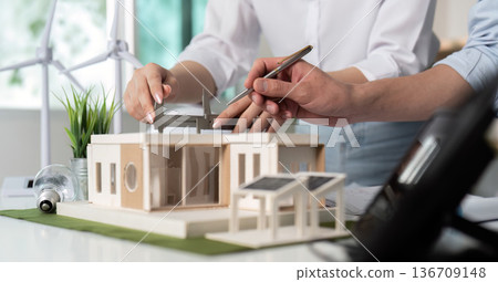 Two people are working on a model of a house 136709148