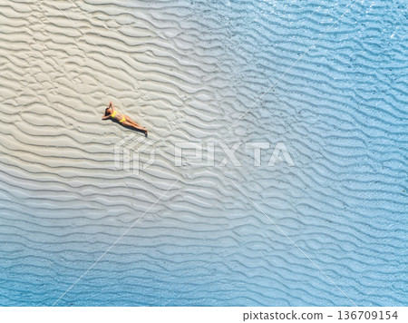 Aerial view of sporty woman in bikini in clear turquoise sea Aerial view of sporty woman in bikini in clear turquoise sea 136709154