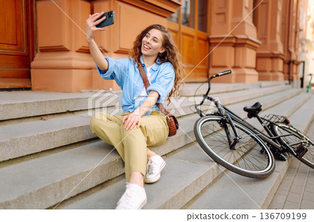 Woman using mobile phone while walks with a bicycle. Selfie time. People, blogging and lifestyle. 136709199