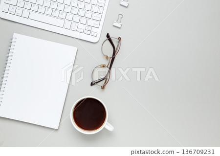 Cozy workspace with coffee cup, keyboard, glasses and notebook creating focused morning atmosphere 136709231
