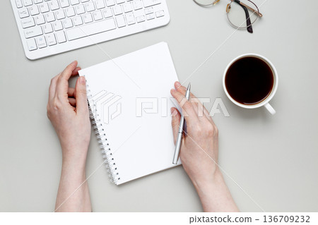 Woman writing on  notebook at organized workspace with stationery items 136709232