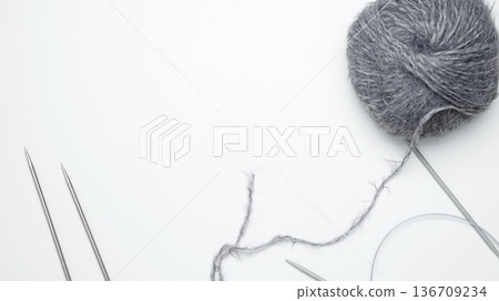 Yarn ball with assorted knitting needles arranged on table for knitting work 136709234