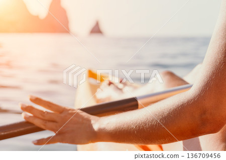 Kayaking Ocean Hand Paddle Close-up of a hand paddling a kayak in the ocean with rocky cliffs in the background. 136709456