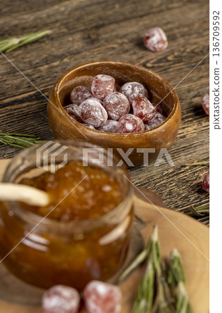 orange jam with dried kumquat fruits in sweet sugar syrup, sweet jam for making desserts in a round jar on a wooden table, orange jam made from oranges and fresh citrus fruits 136709592