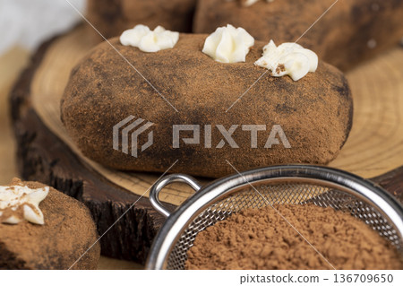 sweet brown pastry potatoes are lying on a serving board and paper, sweet classic cake from butter and a large amount of cocoa mixed with sponge cake and cognac, cocoa powder sweet brown pastry potatoes are lying on a serving board and paper, sweet classic cake from butter and a large amount of cocoa mixed with sponge cake and cognac, cocoa powder 136709650