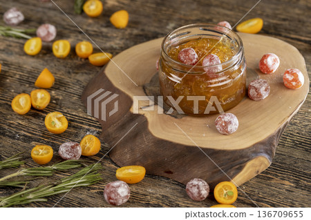 jam with dried kumquat fruits in sweet sugar syrup, sweet jam for making desserts in a round glass jar on a wooden table, orange jam made from oranges and fresh citrus fruits jam with dried kumquat fruits in sweet sugar syrup, sweet jam for making desserts in a round glass jar on a wooden table, orange jam made from oranges and fresh citrus fruits 136709655