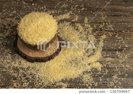 white ground dry hard rice, poured before cooking, poured natural polished rice on the table before cooking, The rice is poured into a bowl made from coconut shells white ground dry hard rice, poured before cooking, poured natural polished rice on the table before cooking, The rice is poured into a bowl made from coconut shells 136709667