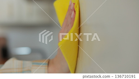 Woman cleaning the kitchen wall. Cleaning, hands and spray bottle with person in kitchen of home for chores, housework or hygiene. Woman cleaning the kitchen wall. Cleaning, hands and spray bottle with person in kitchen of home for chores, housework or hygiene. 136710191