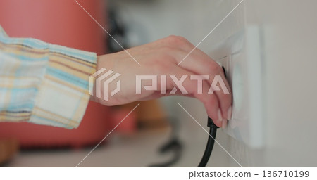 Woman pulls out the electrical plug in socket wire. Close-up power socket. Woman pulls out the electrical plug in socket wire. Close-up power socket. 136710199