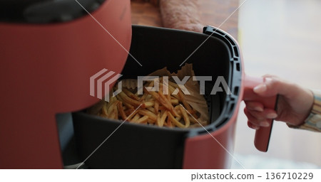 Woman at home using trendy kitchen gadget, deep fryer, selecting program. Woman at home using trendy kitchen gadget, deep fryer, selecting program. 136710229