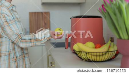 Woman hand throwing catching tasty apple into the air, shot in fine modern kitchen. 136710253