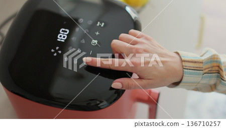 Woman cooking tasty chicken nuggets in air fryer. Healthy food for diet eating. Woman cooking tasty chicken nuggets in air fryer. Healthy food for diet eating. 136710257