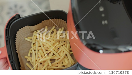 Air-frying delicious French fries cooked by airfryer at home. Healthy food for diet eating. 136710278