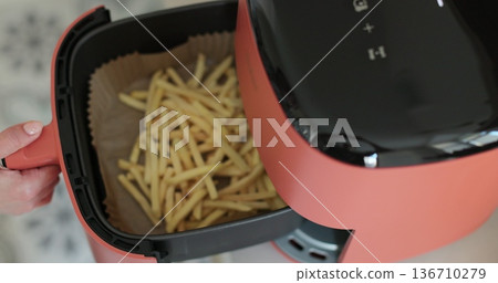 Tasty crispy french fries cooked at air fryer. Fried potatoes,cooking with hot air wedge potatoes,hand pulling open Air fryer oil-free frying pan. Tasty crispy french fries cooked at air fryer. Fried potatoes,cooking with hot air wedge potatoes,hand pulling open Air fryer oil-free frying pan. 136710279