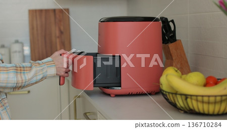 Modern air fryer in kitchen - concept of preparing a healthy food. Smart device at home kitchen. Modern air fryer in kitchen - concept of preparing a healthy food. Smart device at home kitchen. 136710284