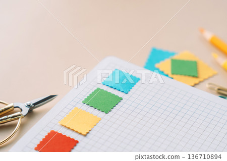 Grid notebook with colorful paper squares and stationery for scrapbooking and journaling on beige background 136710894